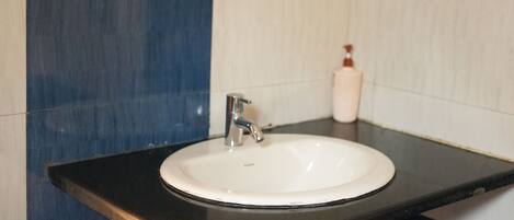 A bathroom with a white sink, a mirror, and a soap dispenser.