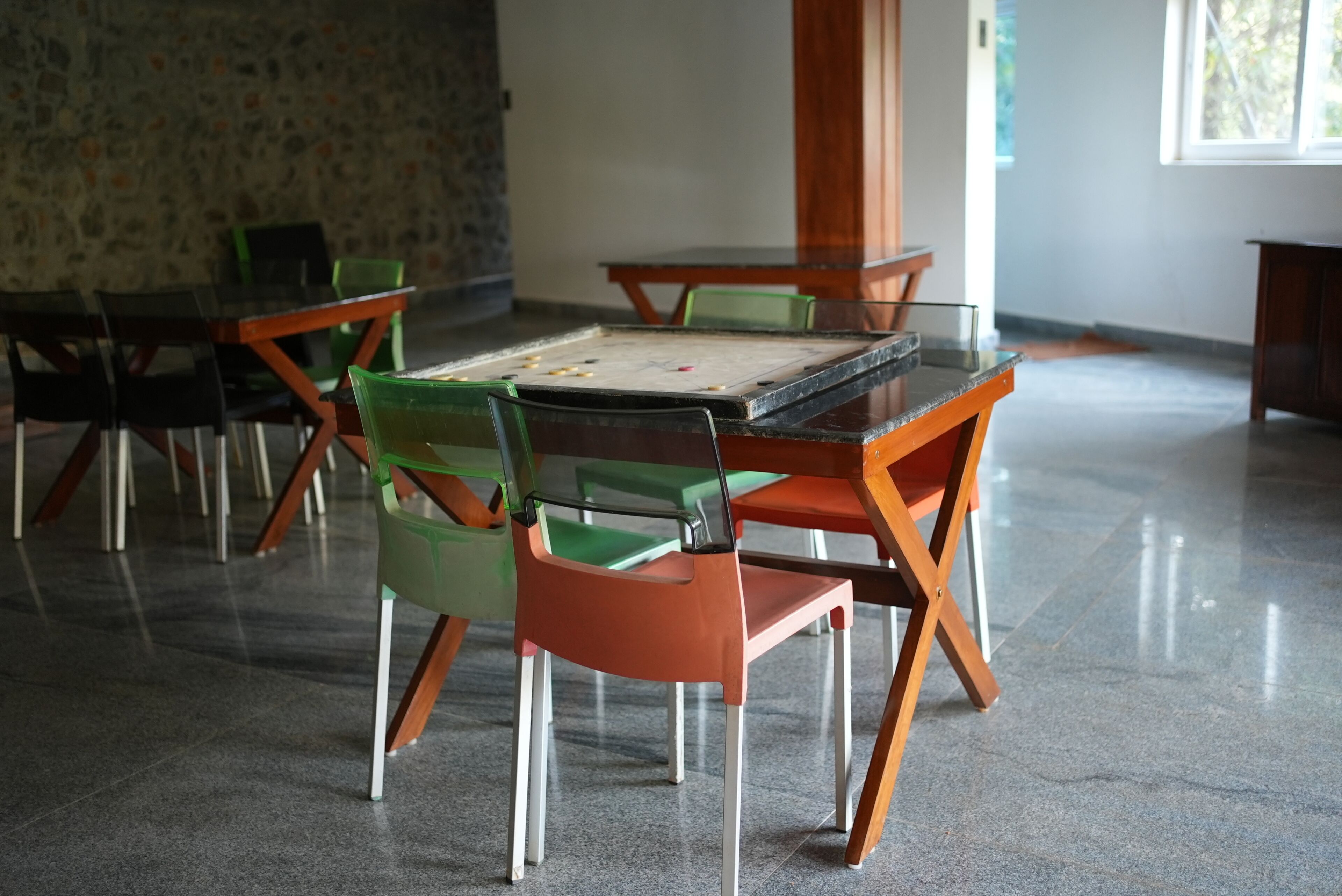 A dining area with a table and chairs, a stone wall, and a window.
