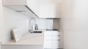 A modern kitchen with white cabinetry, a stainless steel sink, and a kettle on the countertop. - Il Borgo Apartments A3 - Sv-d600-bove3c1a (Finale Ligure)