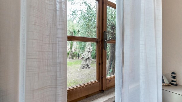 A wooden-framed door with a view of a tree and grass outside. - Il Borgo Apartments B4 - Sv-d600-bove3h1b (Finale Ligure)