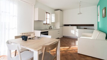 Una cucina funzionale con pensili bianchi, un tavolo da pranzo con sedie e un divano.