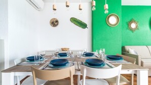 A dining area with a green accent wall, wooden chairs, and blue plates. - Il Borgo Apartments C1 - Sv-d600-navi44atc (Finale Ligure)