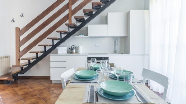 Eine moderne Küche mit weißen Schränken, einer Edelstahl-Spüle und einer Holztreppe.