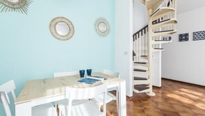 A dining area with a marble table and white chairs, a spiral staircase, and decorative wall mirrors. - Il Borgo Apartments C3 - Sv-d600-navi44c1c (Finale Ligure)