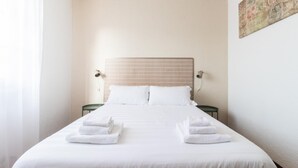 A neatly made bed with white linens and towels, two bedside tables with lamps, and a patterned headboard. - Il Borgo Apartments C3 - Sv-d600-navi44c1c (Finale Ligure)
