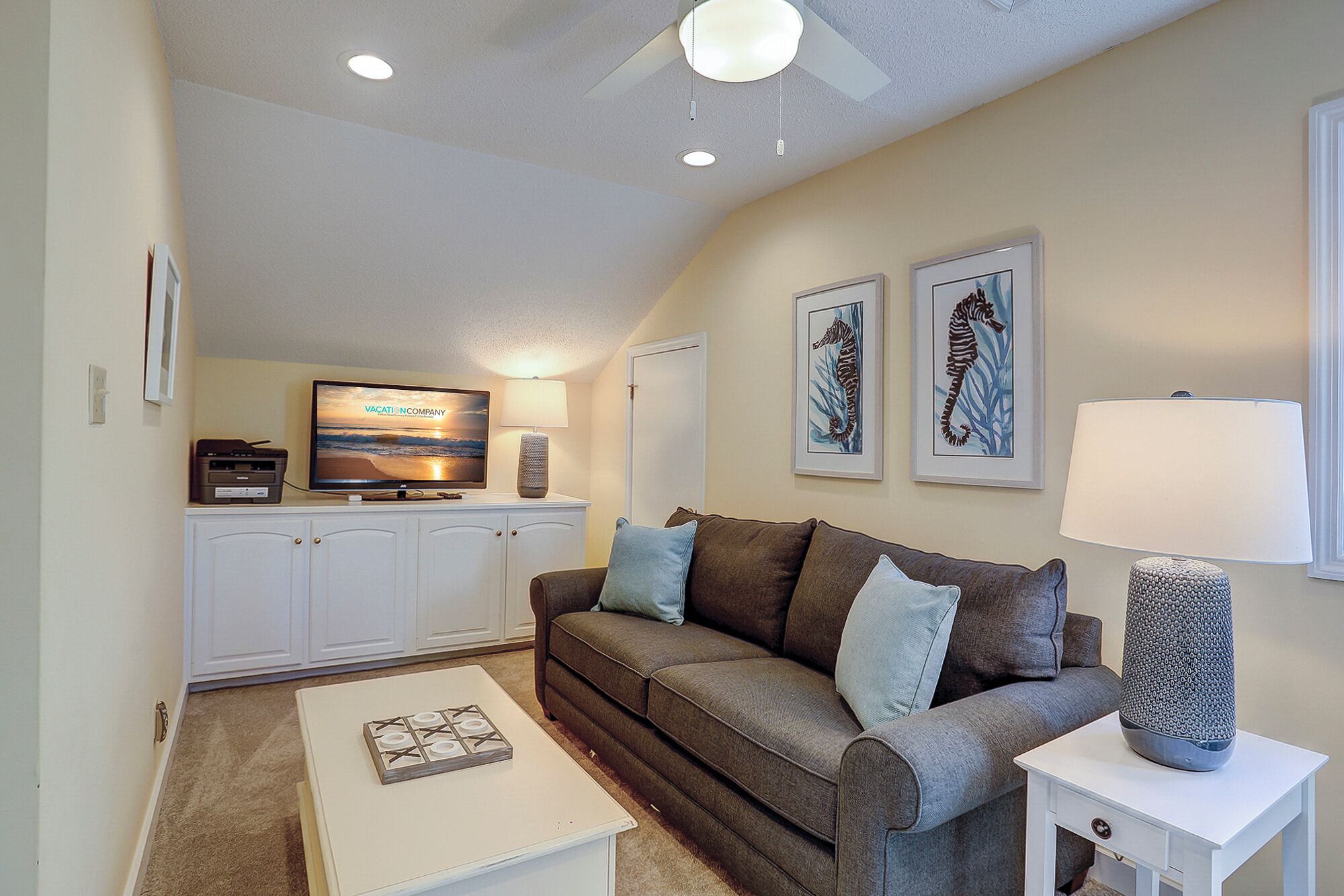A living room with a sofa, a coffee table, a TV, and framed artwork on the wall.
