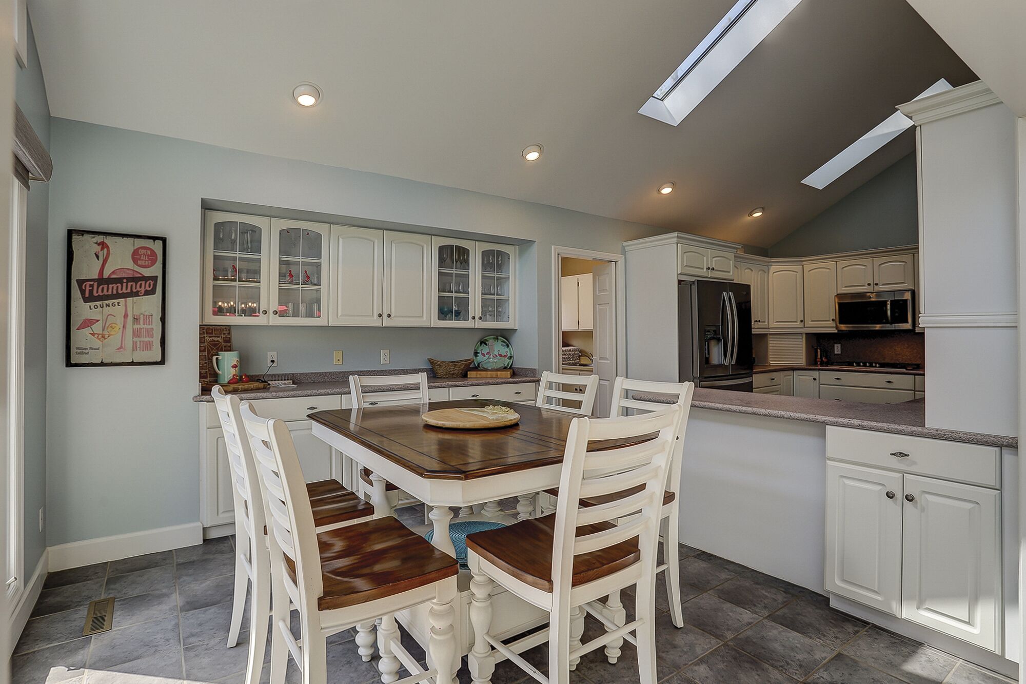 A kitchen with white cabinets, a dining table with chairs, and a refrigerator.