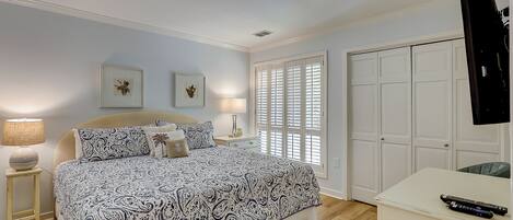 A bedroom with a bed, bedside tables, a desk, and a wardrobe.