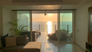 Ein Wohnzimmer mit einer Couch, einem Couchtisch und Blick auf den Ozean bei Sonnenuntergang.