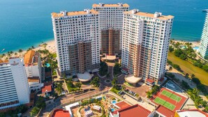 Ein Hochhaus-Hotel mit mehreren Balkonen mit Blick auf einen Strand und das Meer.