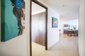 A hallway leading to a dining area with a kitchen in the background.