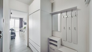 Ein modernes Hotelzimmer mit großem Kleiderschrank, Schminktisch mit Spiegel und einer kleinen Sitzecke mit Tisch und Stühlen.