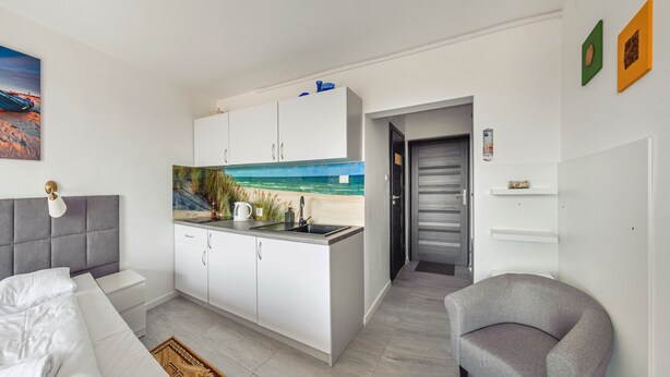 Ein modernes Zimmer mit Küchenzeile, einem Bett und Blick auf den Strand.