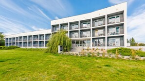 Ein mehrstöckiges Hotel mit Balkonen, Außenbereich zum Sitzen und einem gepflegten Rasen.