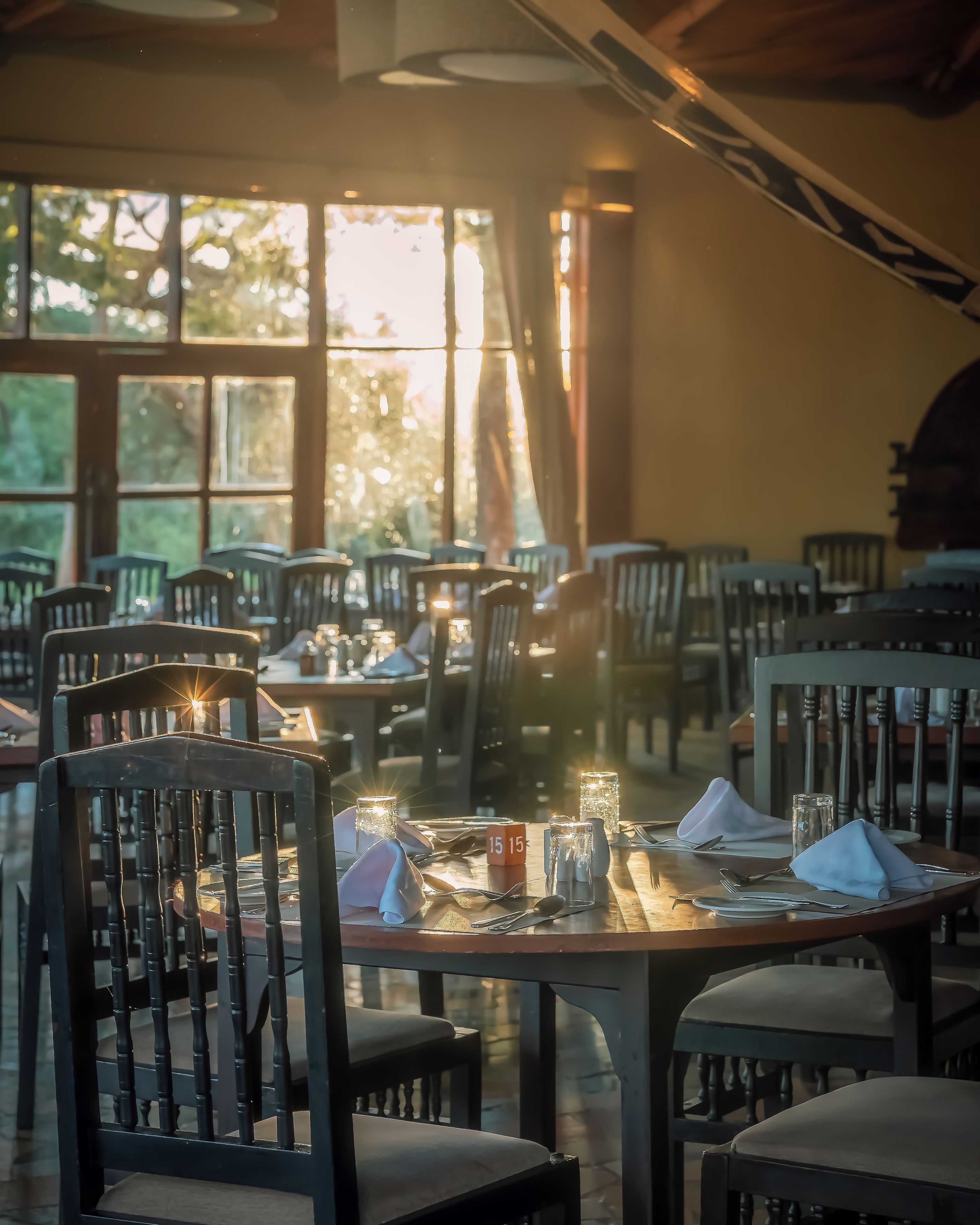 A dining area with tables set for two, chairs, and a candle centerpiece.