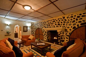 Una sala de estar acogedora con sofás anaranjados, una mesa de centro y una chimenea con pared de piedra.