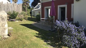 En boligejendom med velholdt græsplæne, terrasse med udendørs møbler og træhegn.