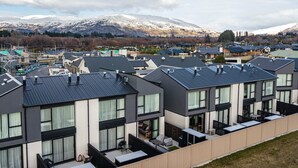 A modern residential area with multi-story houses, a visible road, and a mountain in the background.