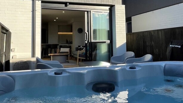 A modern two-story building with a hot tub area in the foreground.