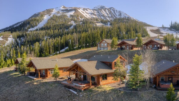 Un complexe touristique composé de plusieurs chalets en rondins, avec une piste de ski et une vue imprenable sur les montagnes.