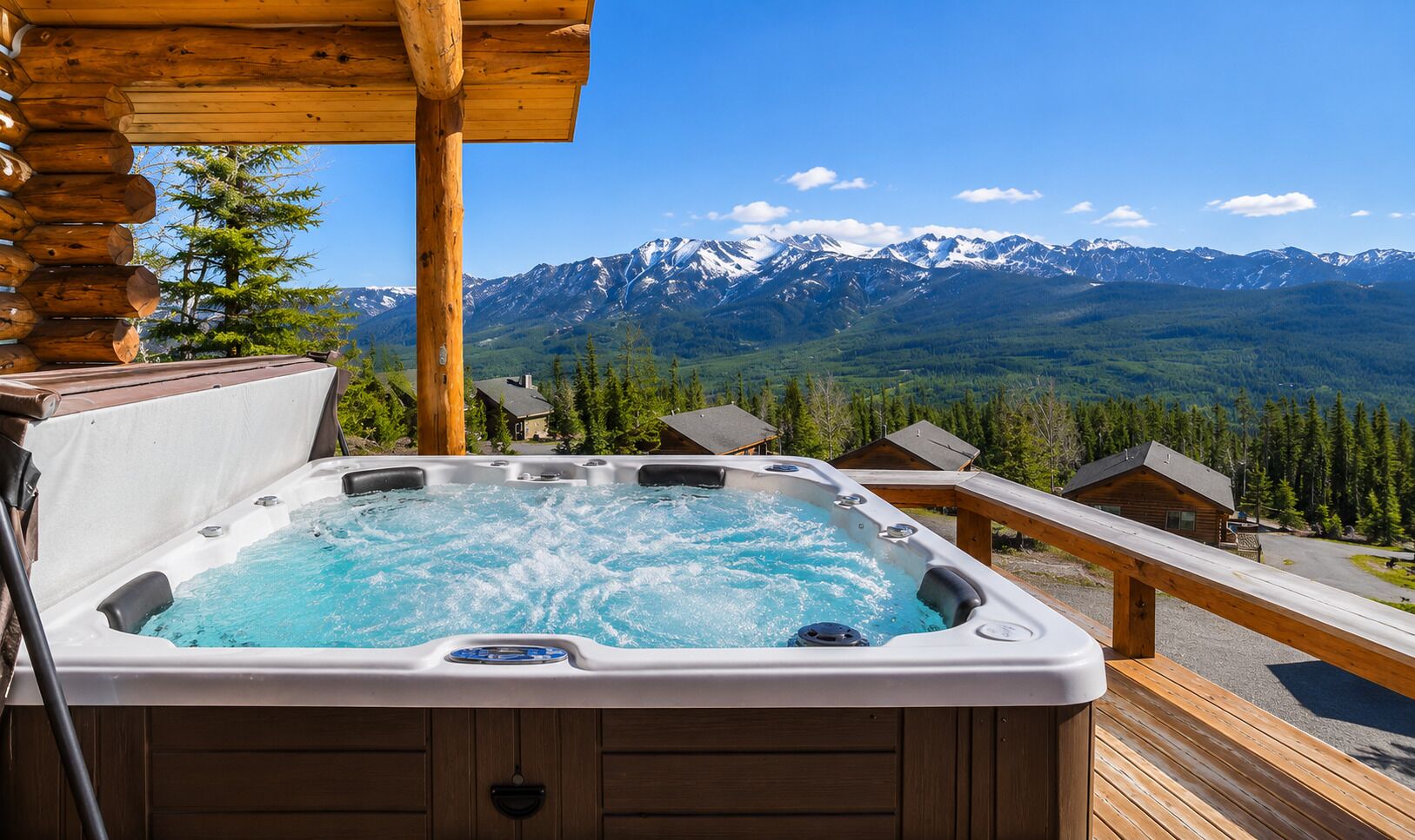 A hot tub on a wooden deck with a mountain view.