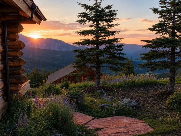 A log cabin with a view of mountains and a sunset.