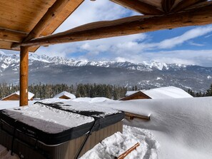 A wooden cabin with a view of snow-covered mountains.