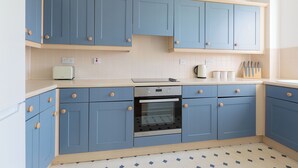 A kitchen with blue cabinets, a built-in oven, and a white countertop. - The Haggerston Flats (London)