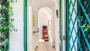 A hallway with a tiled floor, a red cabinet, a television, and a door with a green lattice design.