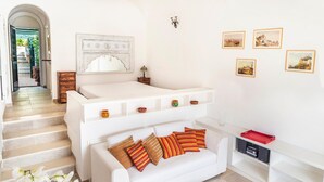 A modern living room with a white sofa, a coffee table, and a staircase leading to an outdoor area.