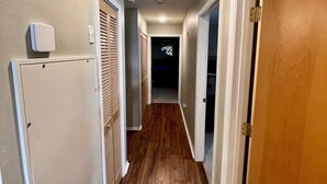 A narrow hallway with wooden flooring, white walls, and a ceiling light.