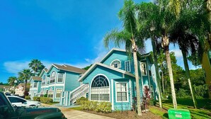 A row of turquoise houses with a driveway and a parked vehicle.