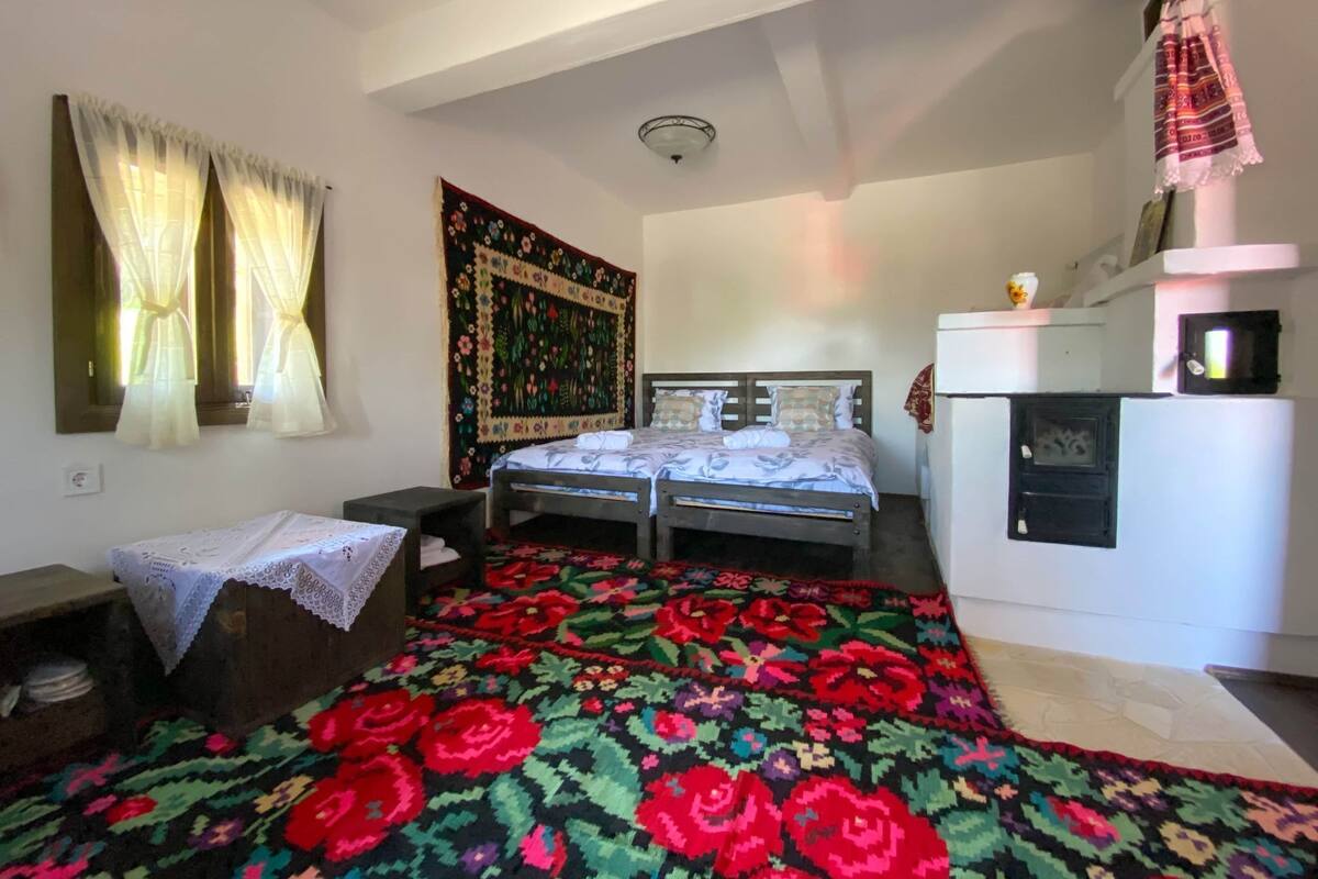 A bedroom with a bed, a small table, a cabinet, and a tapestry on the wall.