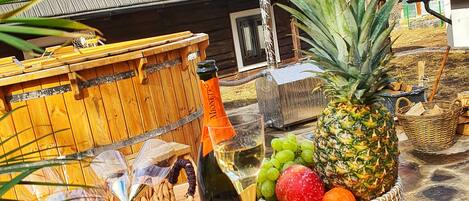 A wooden table with a bottle of wine, a glass, and a fruit basket.