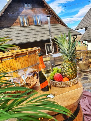 A wooden table with a bottle of wine, a glass, and a fruit basket. - Vatra Boiereasca (Cacica)