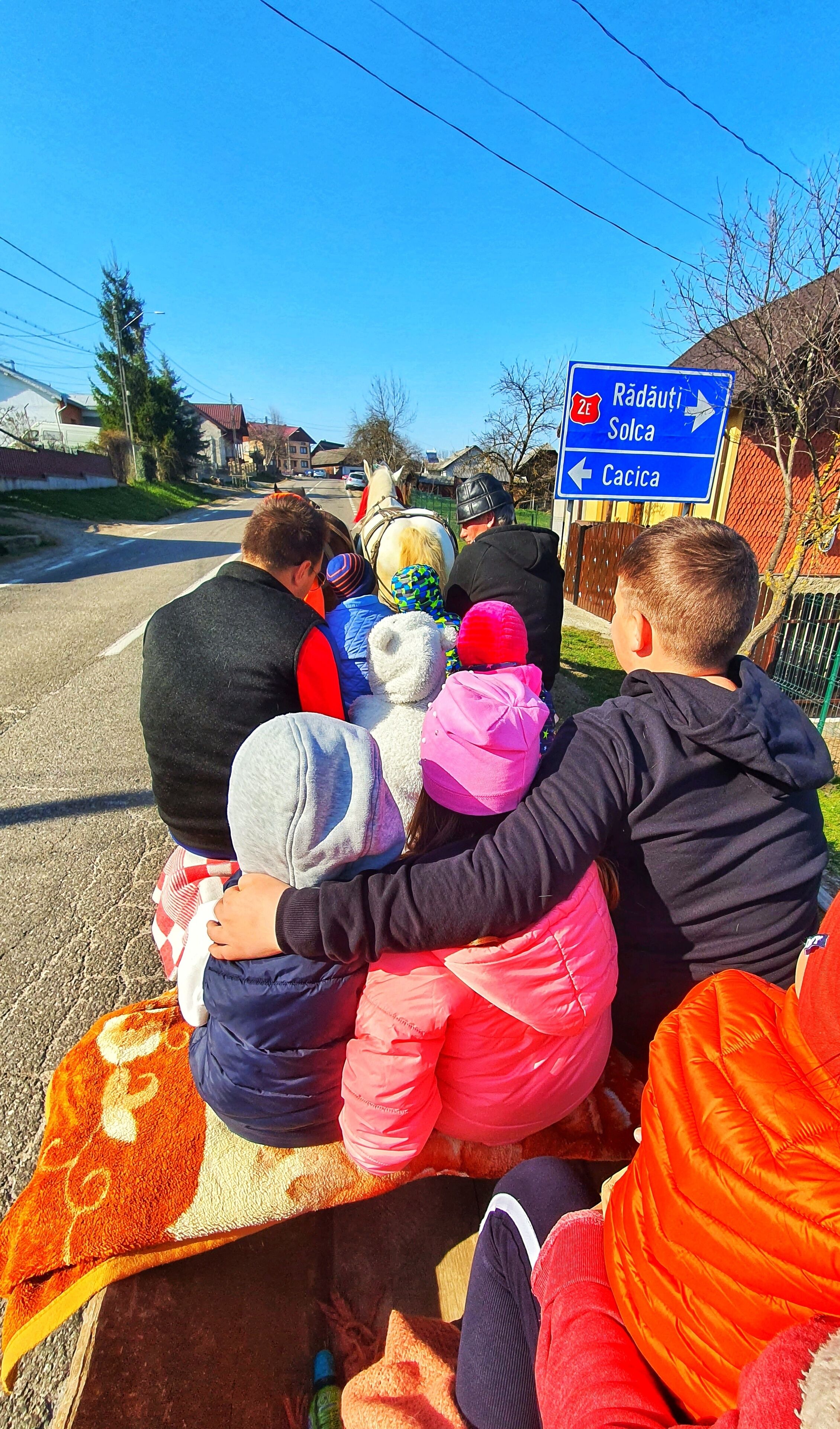 A group of people sitting on a blanket on a road with a directional sign in the background.