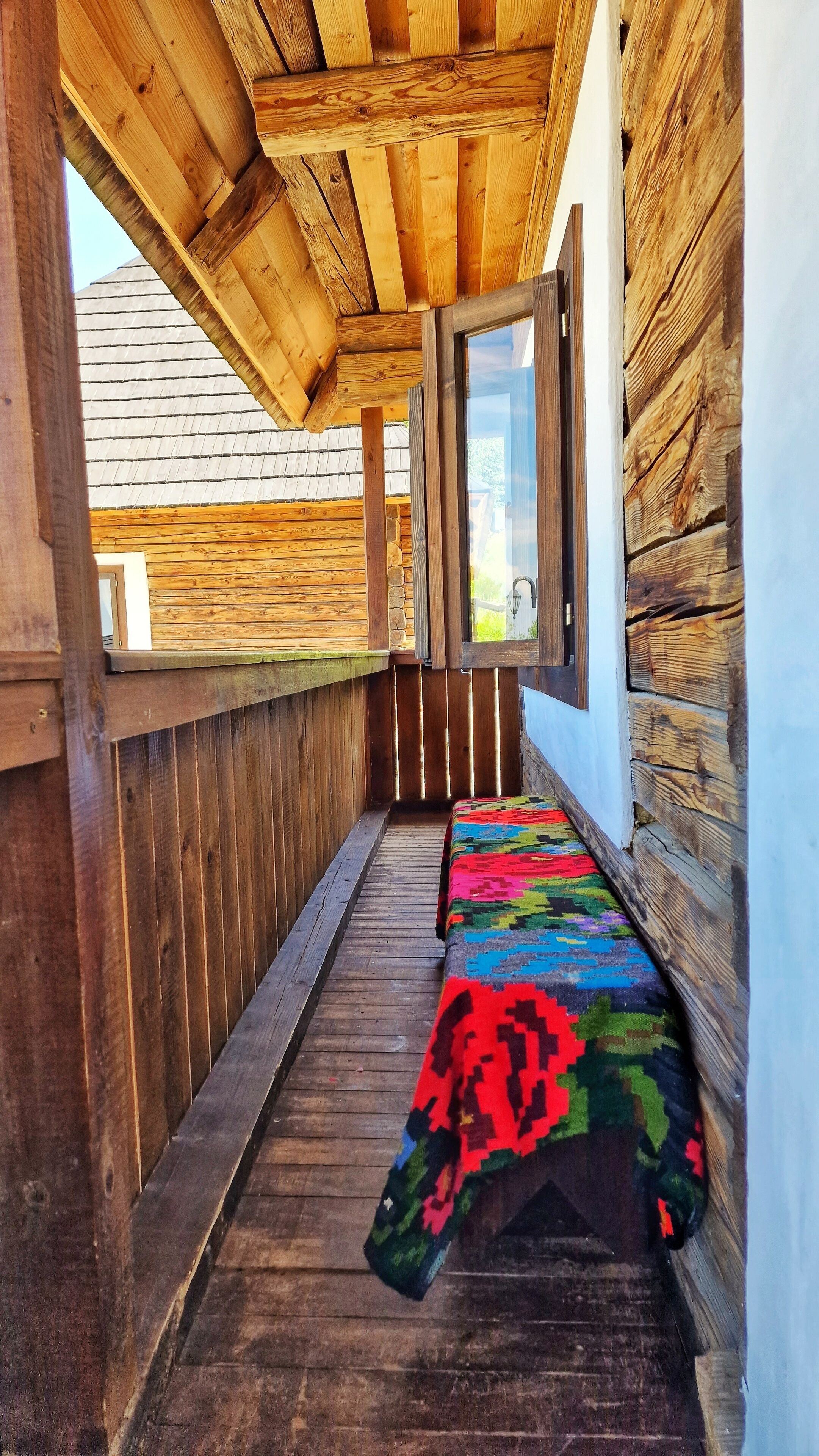 A narrow wooden corridor with a bench and a window.