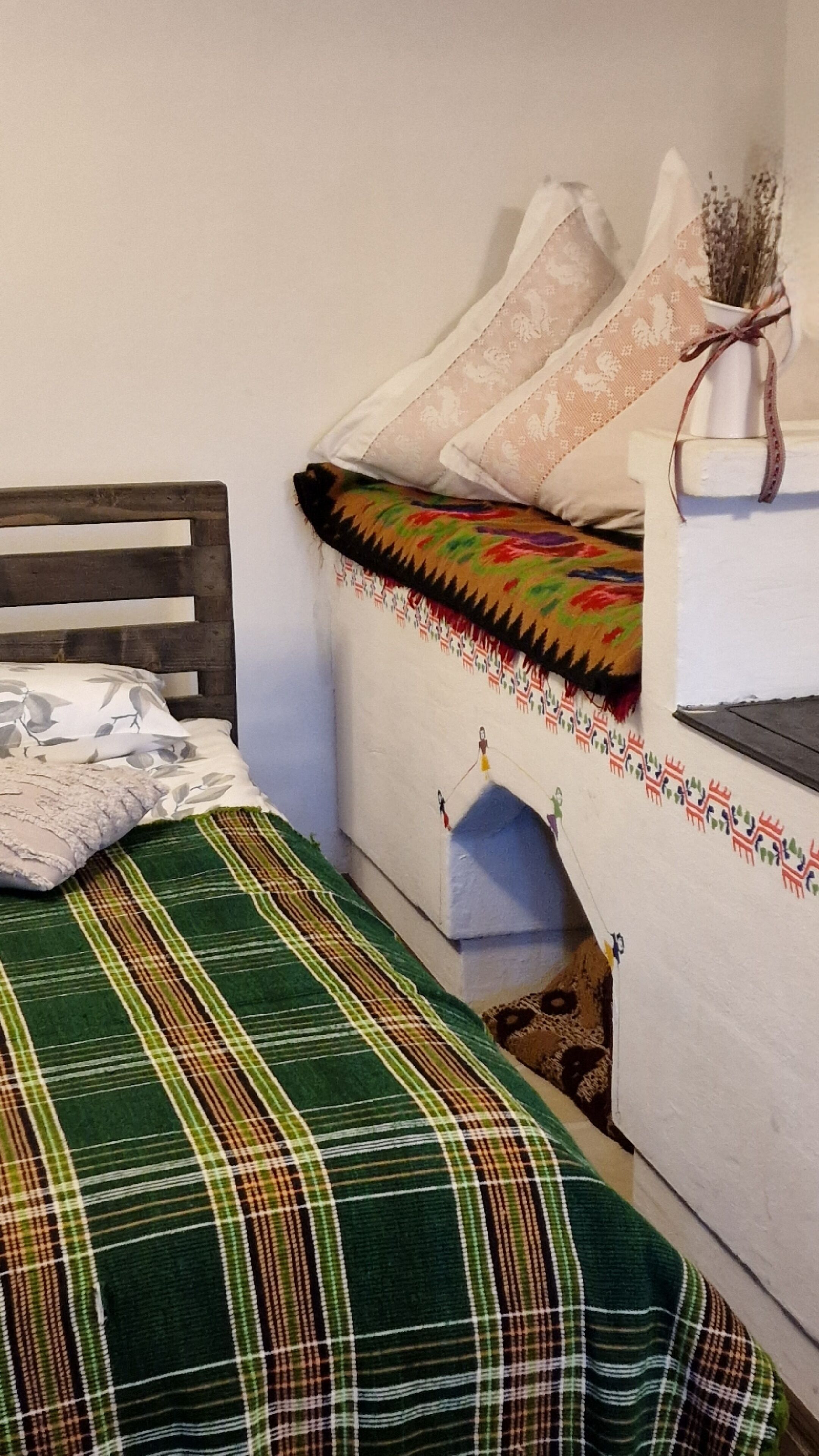Een kamer met een bed, een klein tafeltje en een decoratieve vaas.