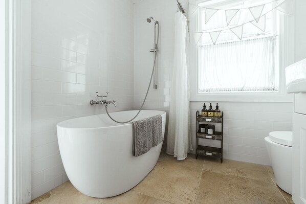 A modern bathroom with a freestanding bathtub, a showerhead, and a toilet.