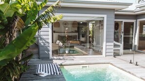 A modern house with a swimming pool, a covered patio, and a glass door leading to an outdoor seating area. - 'Serenity Gerringong' Designer Beach House (Werri Beach)