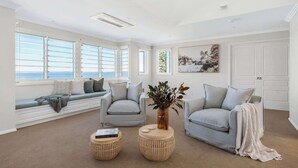 Un salon spacieux avec une grande fenêtre, un canapé, deux fauteuils, une table basse et un vase décoratif.