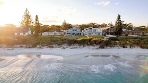 Une propriété située en bord de mer, comprenant plusieurs maisons, une plage de sable et un ciel dégagé.