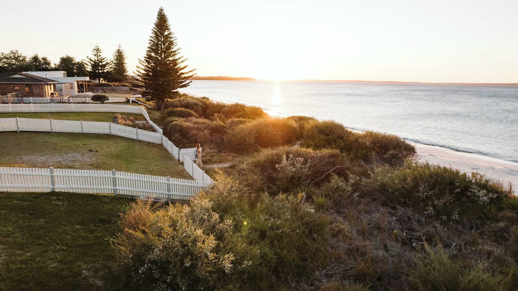 A coastal property with a fenced garden, a pathway, and a view of the sea.