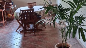 Un coin repas avec une table et des chaises, une plante en pot et une fenêtre donnant sur un paysage verdoyant.