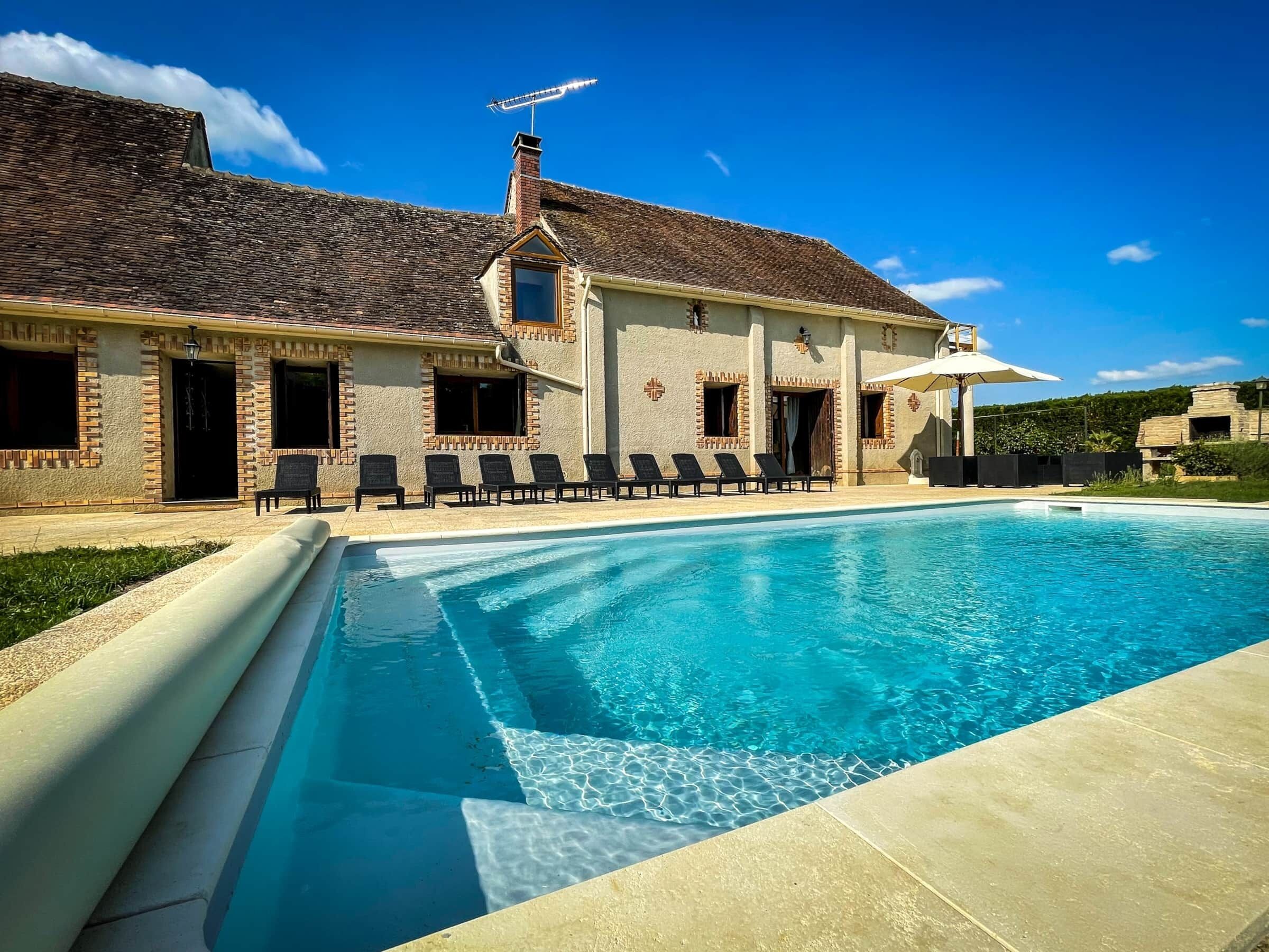 A large swimming pool with a clear blue water surface, surrounded by a paved deck.