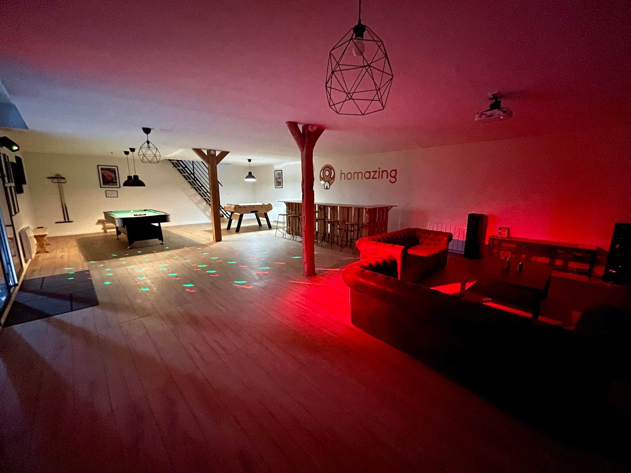 Een kamer met een pooltafel, een rode bank, een bar en een trap.
