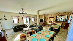 A spacious living area with a dining table set for six, a fireplace, and a stone wall. - Villa Cocorico (45) 30 pers-piscine-1h30 Paris (Chantecoq)