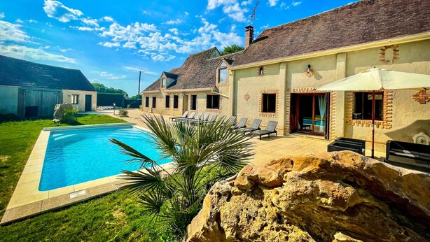 A poolside area with a large pool, lounge chairs, and a rock formation. - Villa Cocorico (45) 30 pers-piscine-1h30 Paris (Chantecoq)