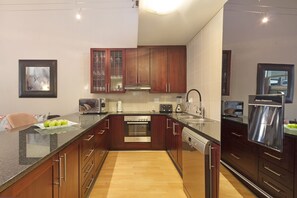 A modern kitchen with dark wooden cabinets, stainless steel appliances, and a granite countertop.