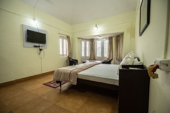 A hotel room with a bed, a TV mounted on the wall, a desk, and a chair.
